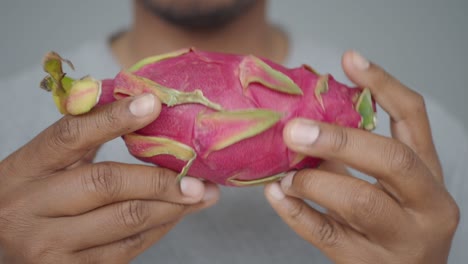 closeup of a man's hands holding a fresh dragon fruit