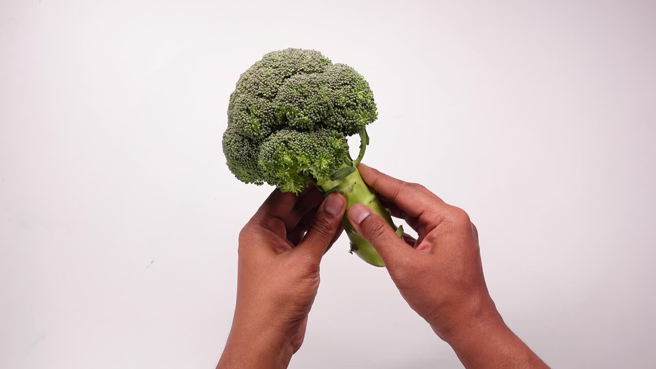 Persona che tiene in mano un broccolo fresco
