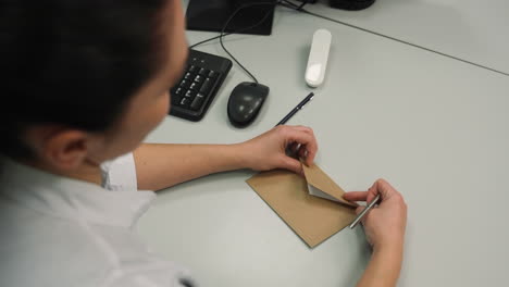 woman putting paper inside of an envelope