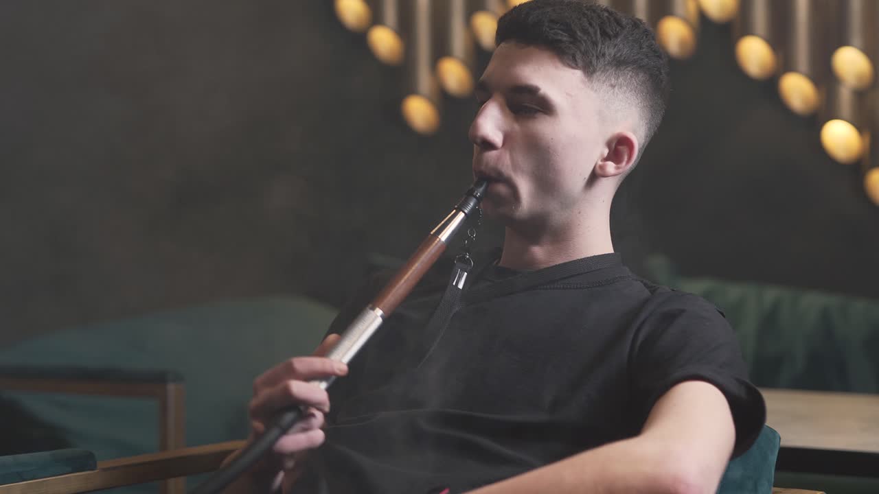 joven fumando narguile y haciendo trucos de humo