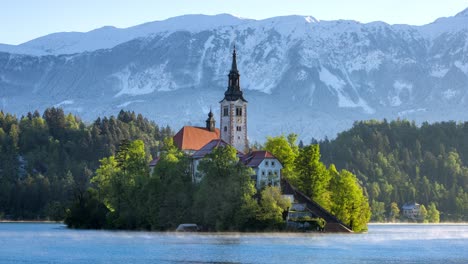 the church of assumption of maria on a spur in the middle of lake bled in slovenia with the morning misty veil rolling around it