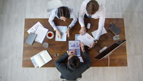 Top-View-Shot-Of-Business-Consultant-And-Businesspeople-Sitting-At-Table-And-Discussing-Documents