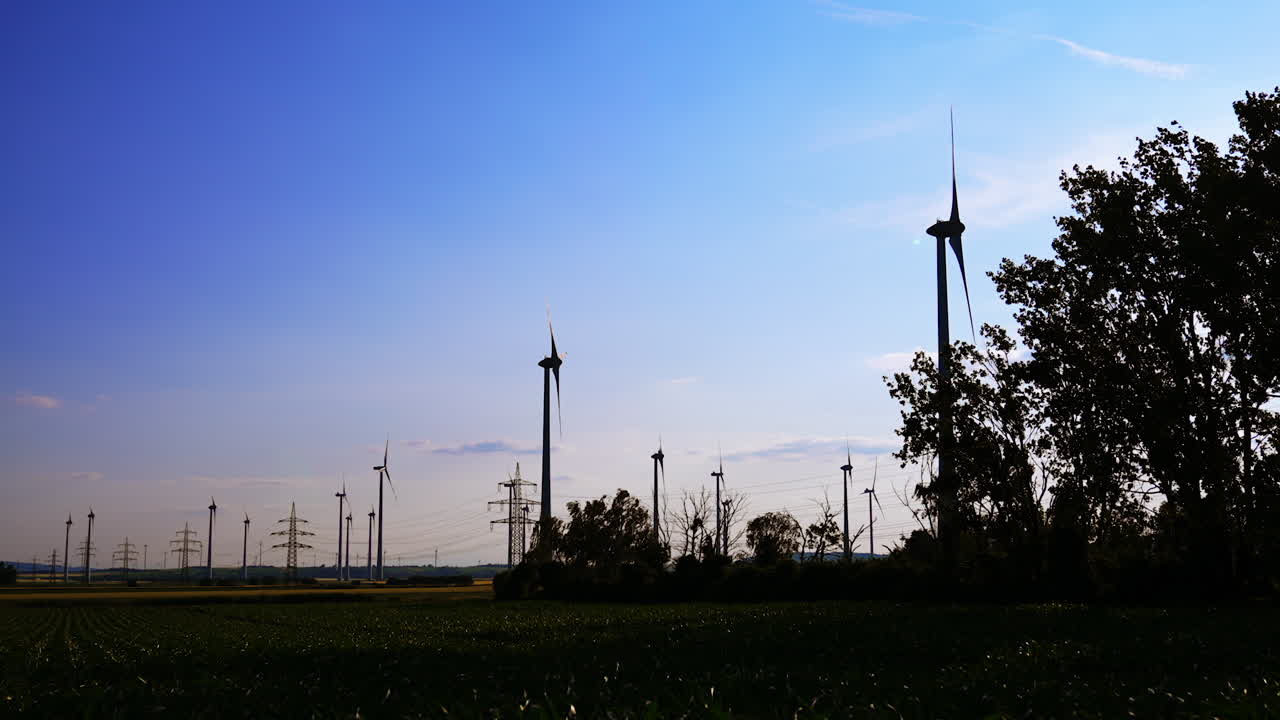 Wind turbines generate energy at sunset. Wind turbines stand tall against a colorful sunset, harnessing renewable energy amidst an open green landscape