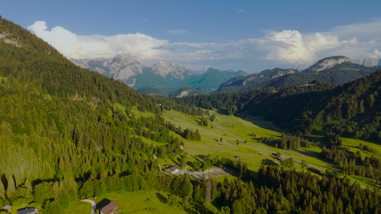 Nuvole drammatiche sopra cime montuose alpine, foresta e campi verdi nella valle di Unken Heutal, Austria