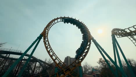 handheld from an inverted curve, high speed roller coaster going around on the rails, sunny day at an amusement park