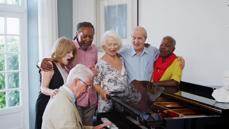 group of seniors standing by piano and singing together