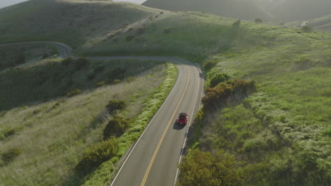 Aerial-drone-shot-follows-a-red-Porsche-1993-Carrera-S-cruising-through-the-mountains-of-Malibu