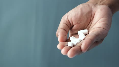 close-up of a hand holding a pile of white pills