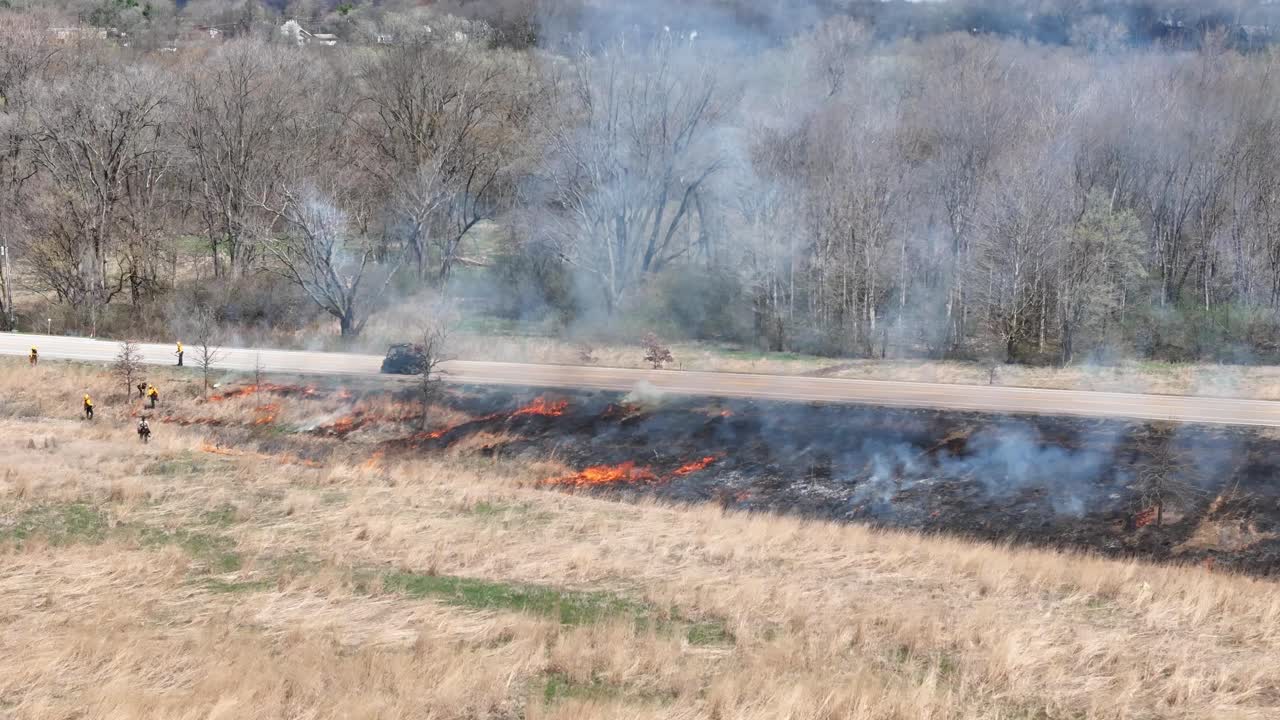 Drone shot showing Firefighters rush to combat wildfire using a controlled fire burn