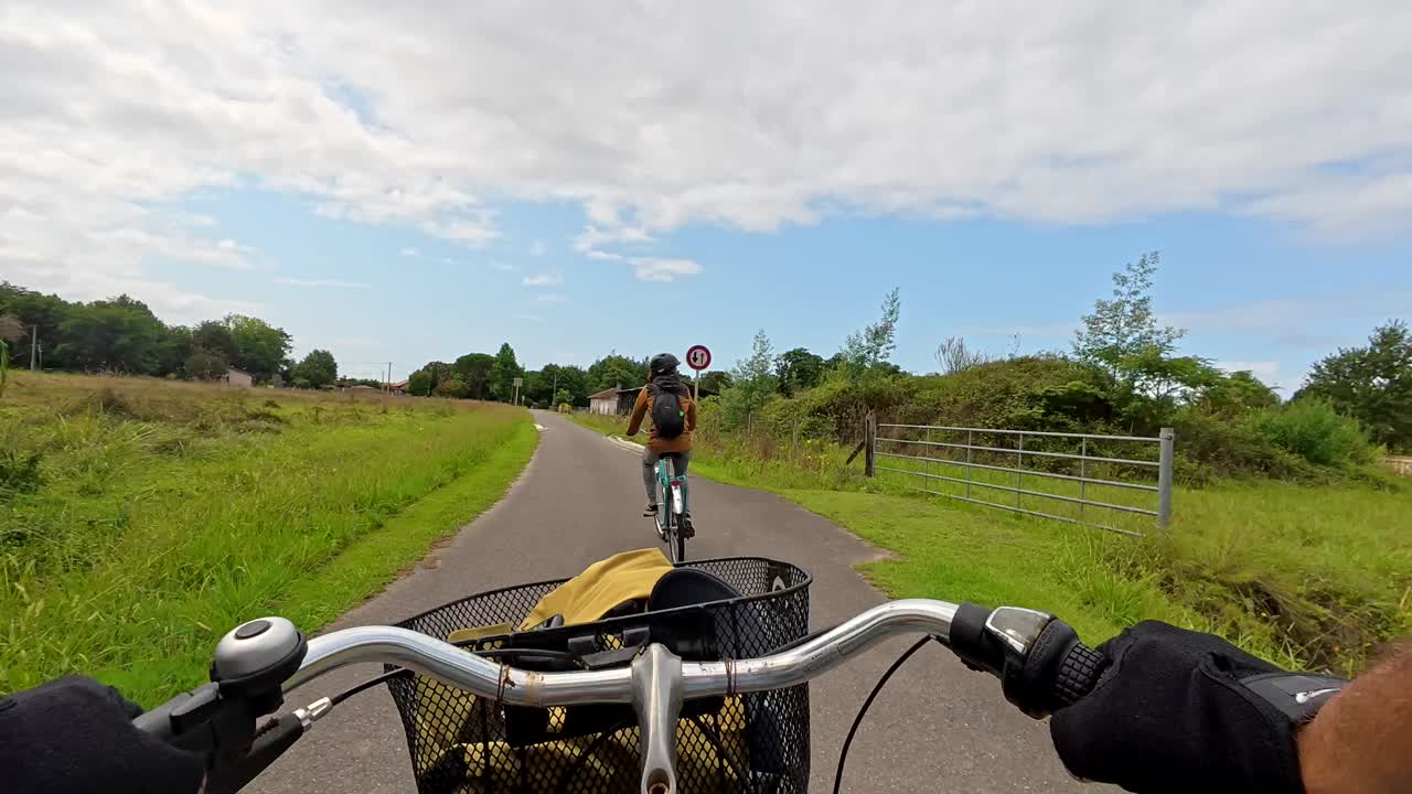 Punto de vista de una persona en bicicleta en una carretera rural, siguiendo a otro ciclista