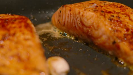 large delicious scottish salmon fish fillets cooking gently and bubbling in butter with garlic cloves for seasoning in frying pan ready to eat 4k