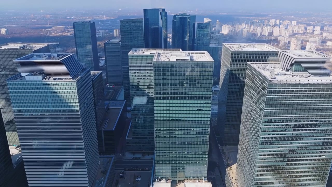 Um horizonte urbano sereno com edifícios altos e arranha-céus contra um céu azul claro, capturado de uma vista aérea em uma paisagem urbana moderna, cena estática sem movimento visível.