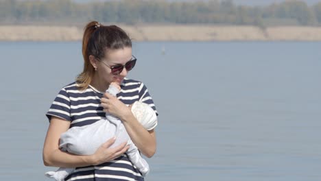 portrait of young mother walks with her infant on a coast