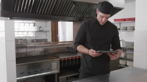 caucasian male chef using tablet in kitchen, slow motion