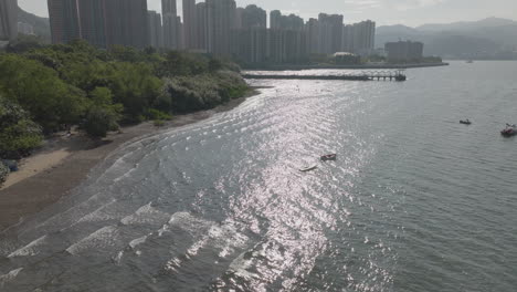 aerial drone shot of boats floating and skyscrapers in hong kong, china