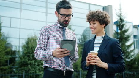business colleagues discussing on a tablet in front of office building