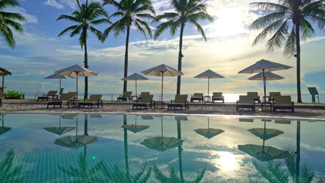 Umbrella-and-chair-around-swimming-pool-in-resort-hotel-for-leisure-travel-and-vacation-neary-sea-ocean-beach-at-sunset-or-sunrise-time