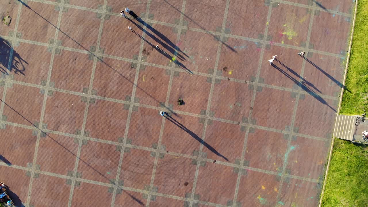 Vue de drone sur des personnes se promenant sur une place en été au coucher du soleil.