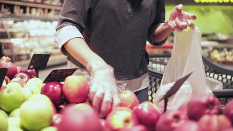 Woman-choosing-red-apples-at-the-grocery-store.-Womans-hand-picks-out-apples-at-the-fruit-and-vegetable-aisle-in-a-supermarket