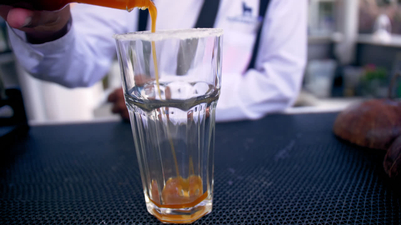 el camarero vierte salsa picante en un vaso en el bar, un primer plano de mano