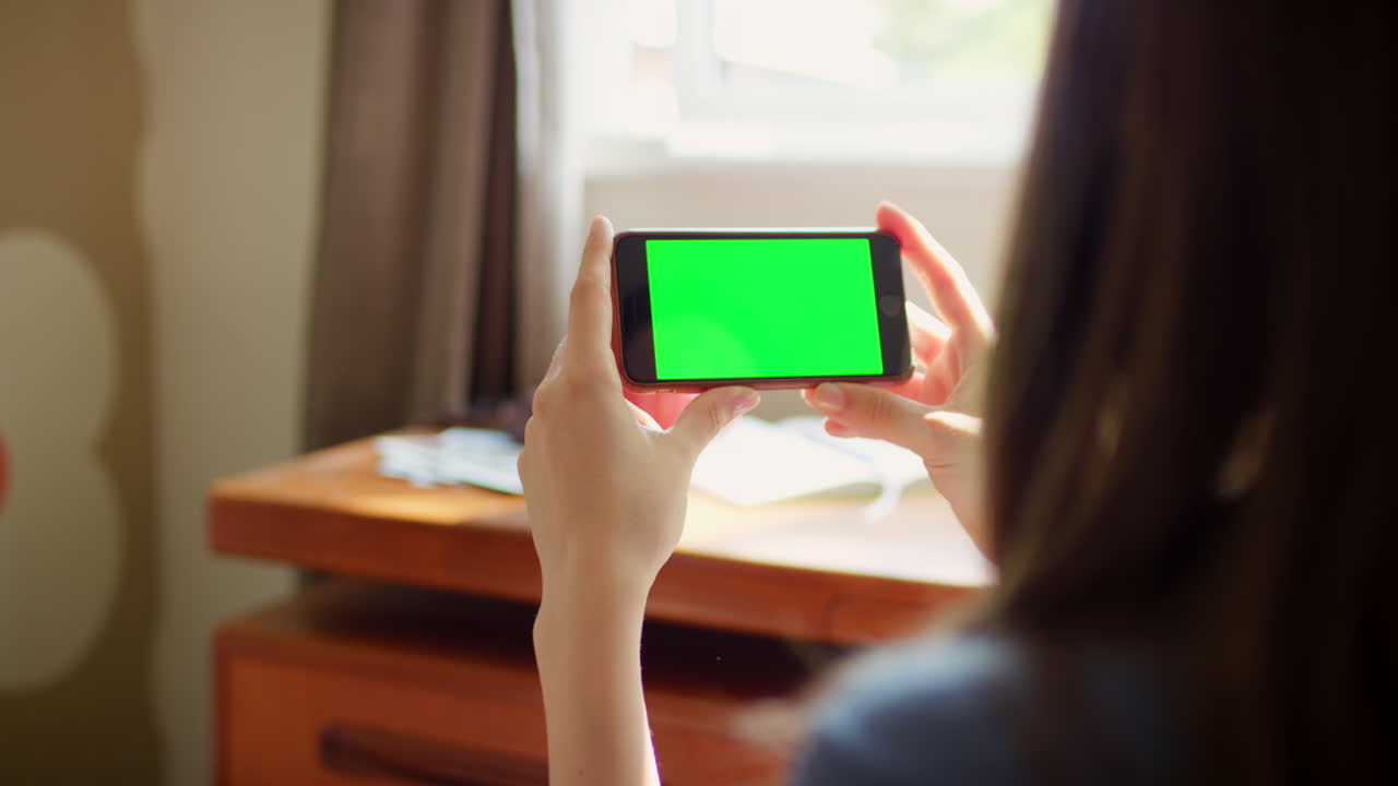 초록색 화면의 스마트폰을 들고 있는 사람