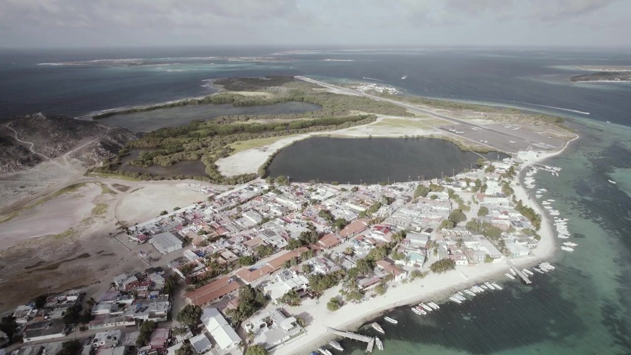 Thị trấn ven biển Gran Roque nhìn từ trên cao, hòn đảo có người ở chính của quần đảo Los Roques ở Venezuela. Cụm nhà làng dày đặc dọc theo bờ cát, với nhiều thuyền nhỏ và bến tàu. 4k Dlog