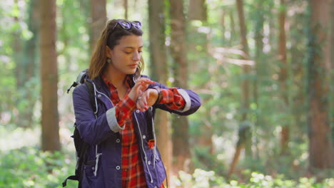 woman on holiday hiking through woods using gps app on smart watch to navigate