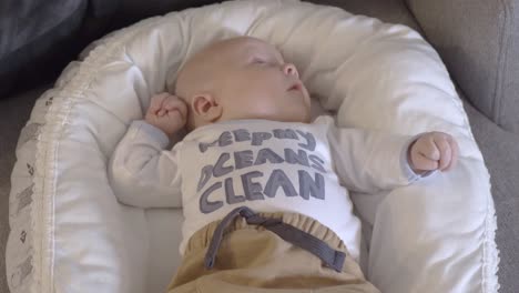 closeup baby lying content in cot pram wearing clean ocean t shirt