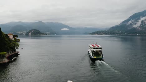 Toma-Aérea-De-Un-Ferry-Que-Sale-De-Varenna-Para-Transportar-Viajeros-En-El-Lago-De-Como