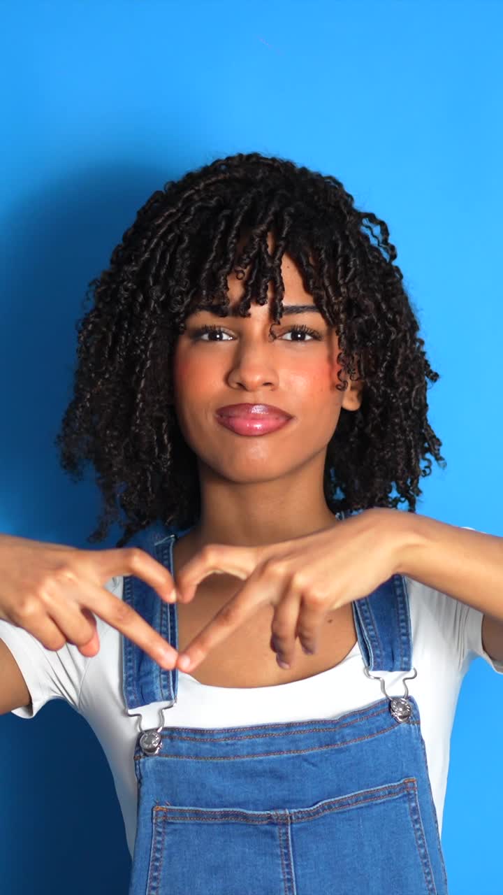 Portrait of a young woman making a heart shape with her hands