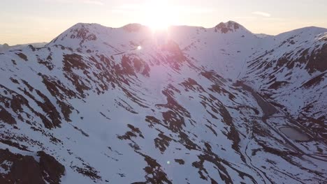 drone view over mountain peak in winter and sun rays