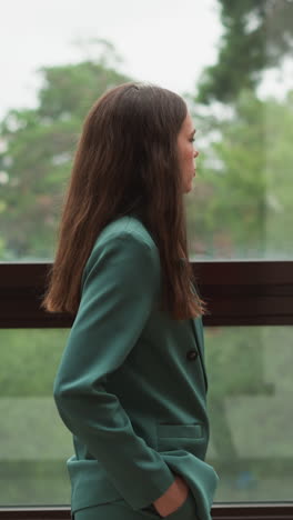 woman takes calm stroll by vast windows. air of despondency settles over office as rumours of impending layoffs circulate among anxious colleagues