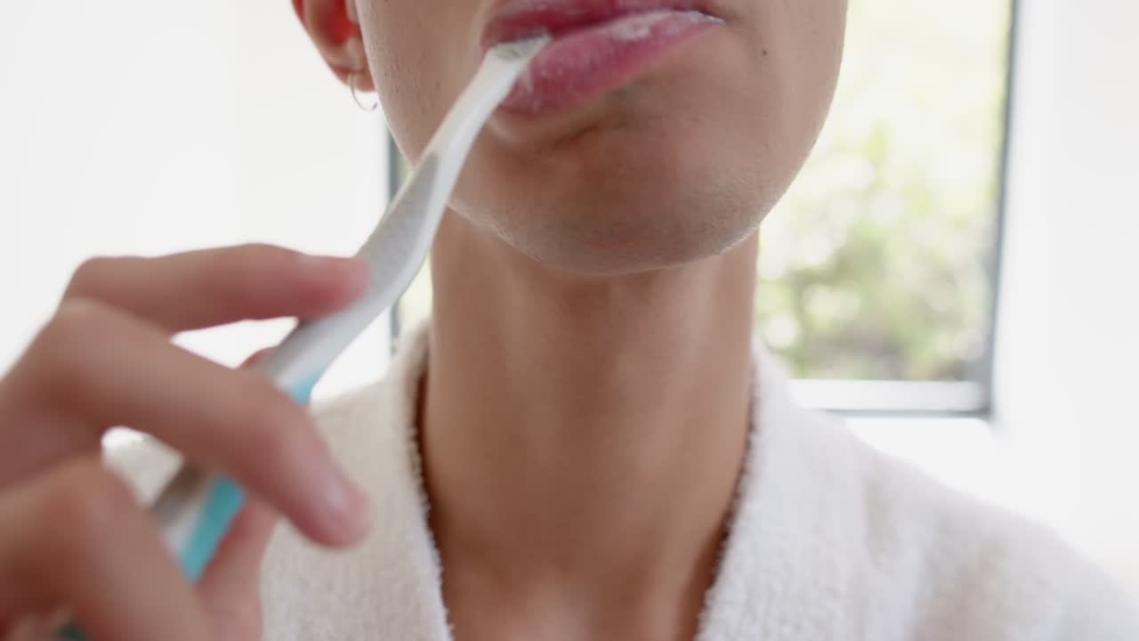 Brushing teeth, person in bathrobe focusing on oral hygiene at home