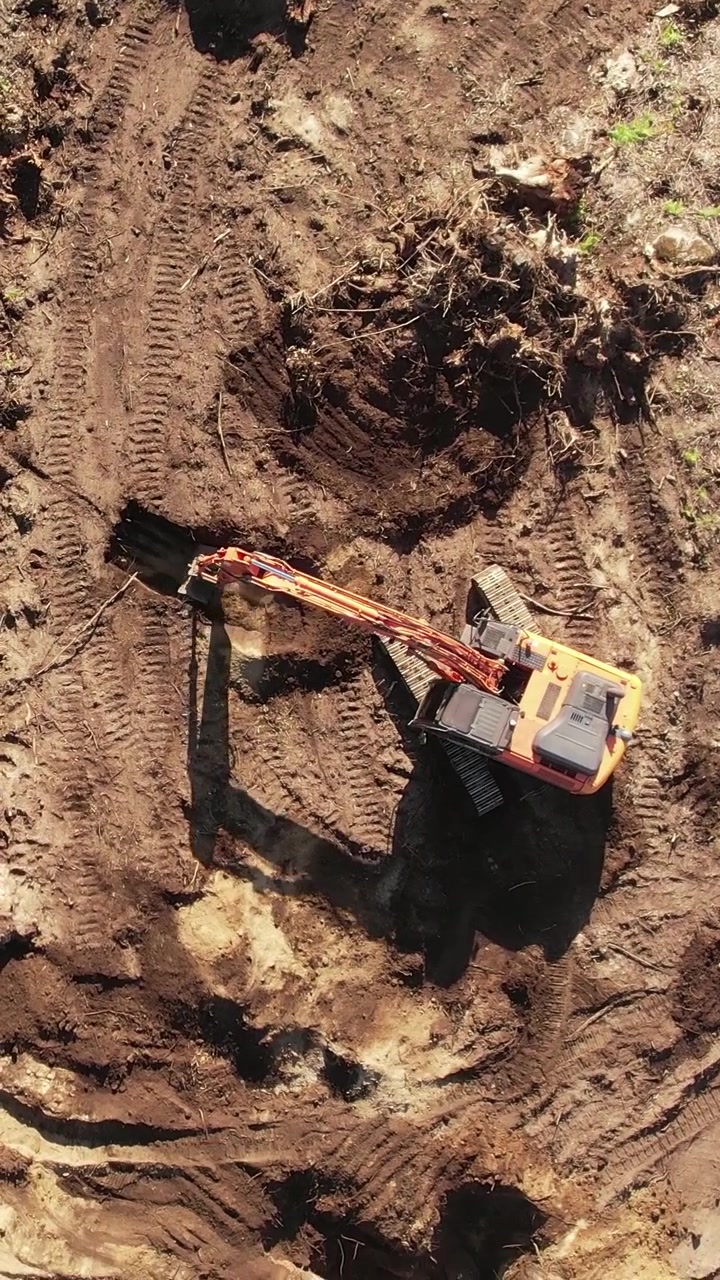 Vista aérea de una excavadora naranja operando en una ladera.