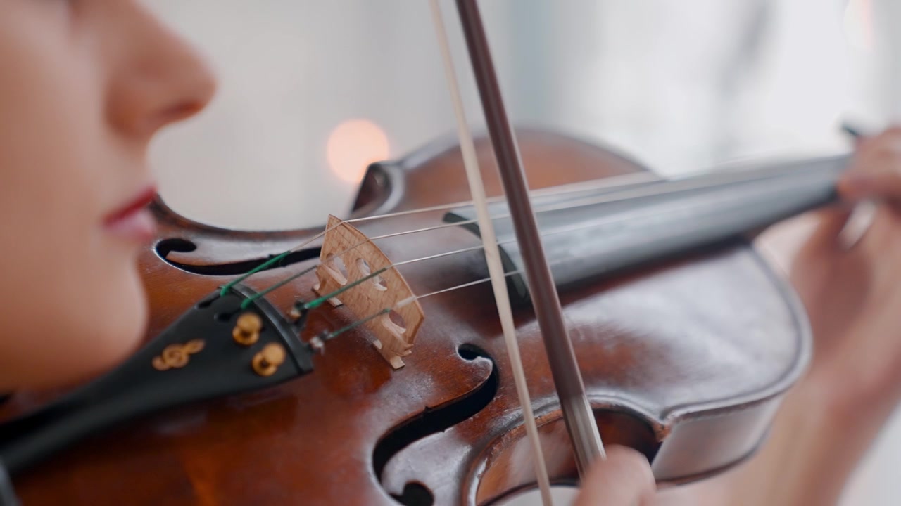 Close-up of a Young Woman Playing the Violin with a Bow