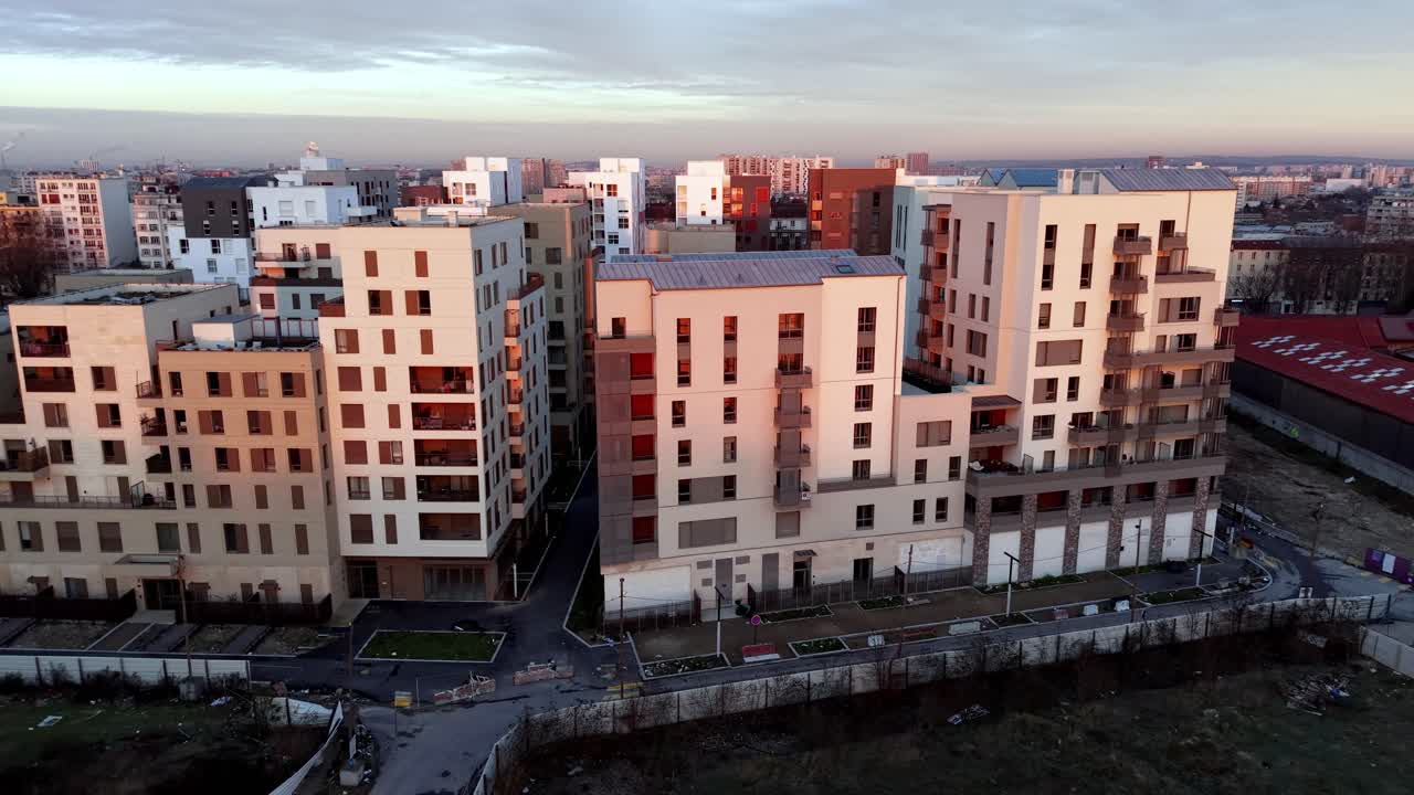 Vista aérea cinematográfica de um empreendimento residencial contemporâneo com fachadas coloridas e arquitetura moderna durante a hora dourada em Paris, França