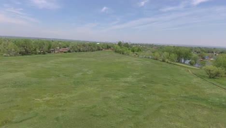 vuelo sobre hierba verde, denver en la distancia