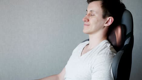 un joven está sentado en el sillón con una almohada de masaje eléctrico