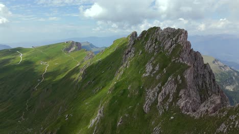 faszinierende luftbilder, die die zerklüfteten felsigen gipfel und die üppig grünen täler der dolomiten in italien unter einem teilweise bewölkten himmel zeigen