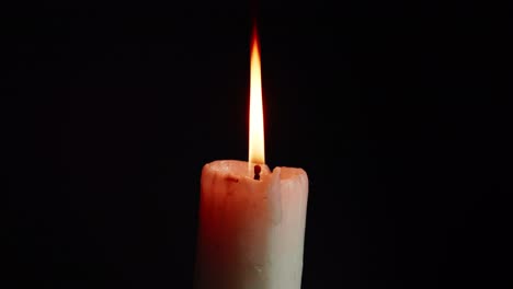 las vitrinas de coloridas velas individuales sobre fondo negro con el efecto de la luz y la cámara lenta
