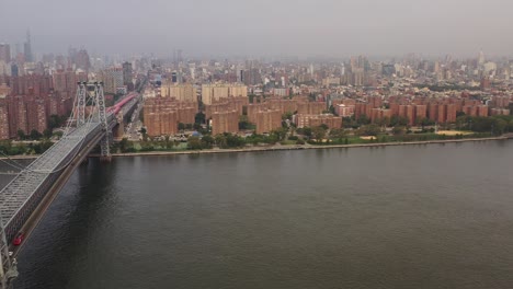 aerial pull away near williamsburg bridge in brooklyn, new york on a gray, cloudy morning