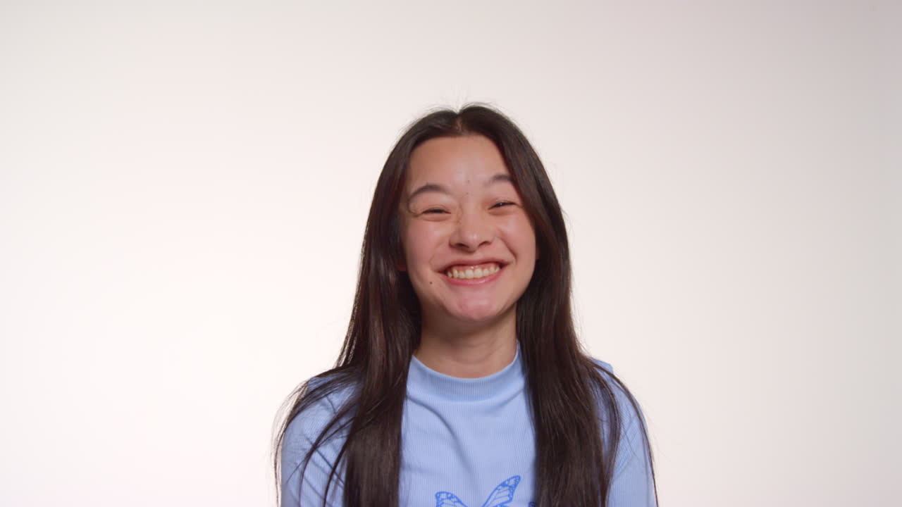 색 스튜디오 배경 앞의 젊은 친구 그룹이 사진 부스 스타일의 초상화를 위해 포즈를 취하고 있습니다.