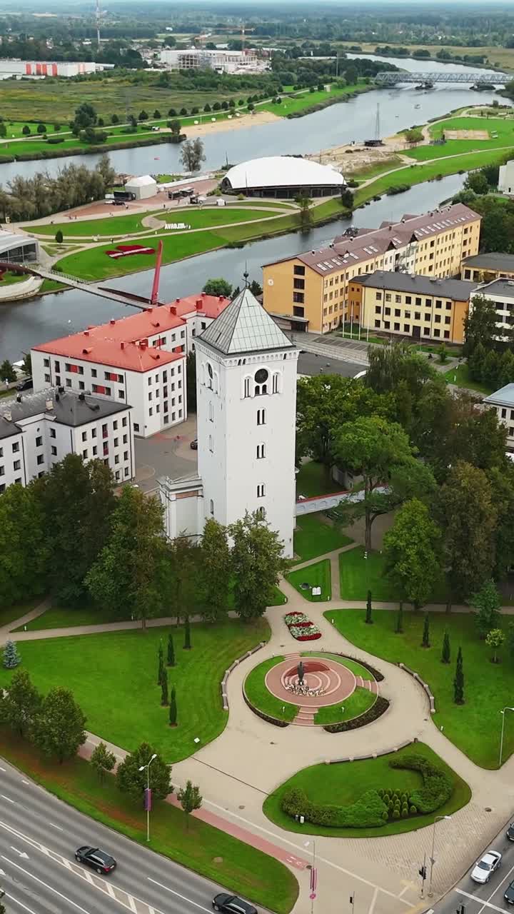 Vertical drone orbit around Jelgava white clock tower and park square