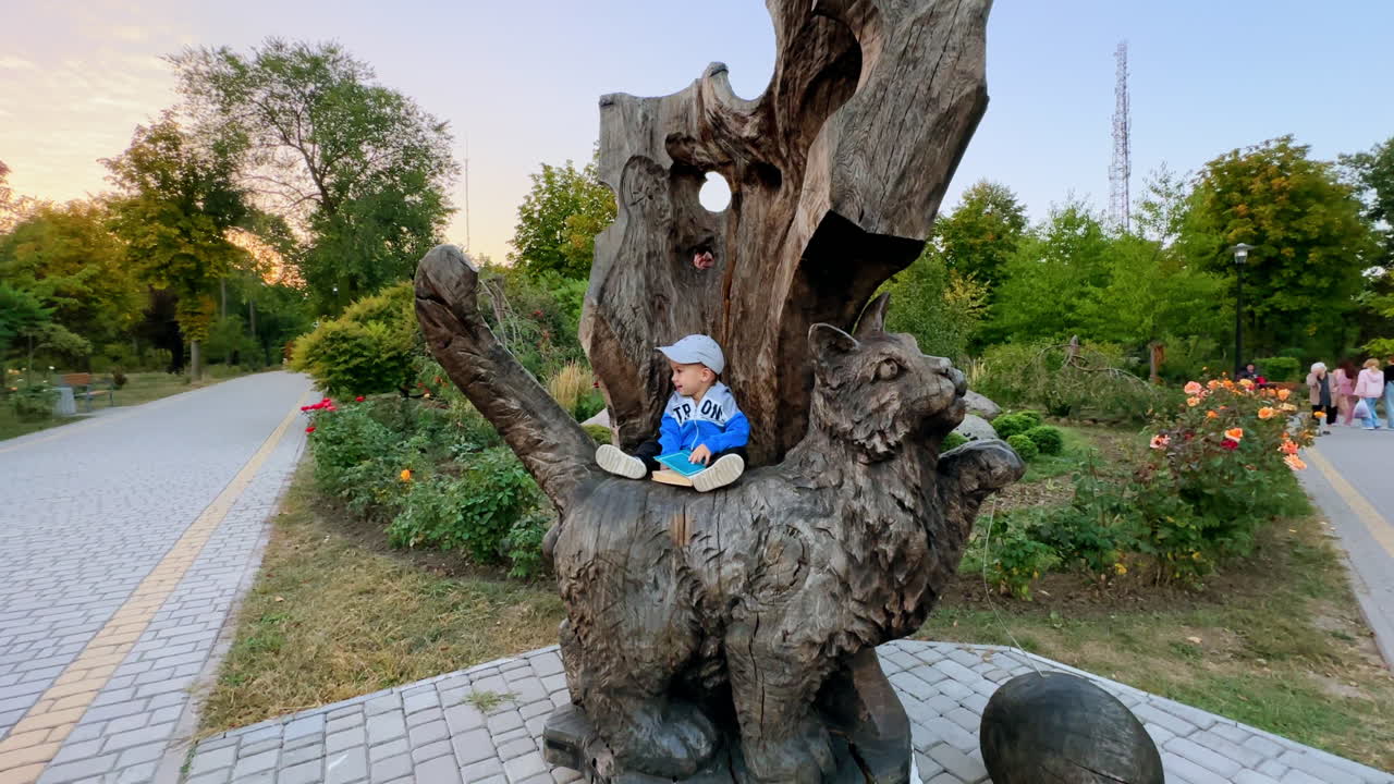 Grandpa plays with his baby grandson sitting on the wooden sculpture of cat. Grandfather hiding from toddler and kid turns to look for him.
