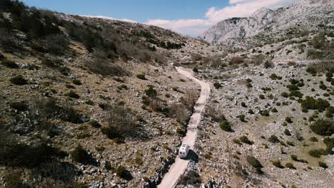 autocaravana solitaria conduciendo por camino de montaña de grava, parque natural de biokovo, croacia