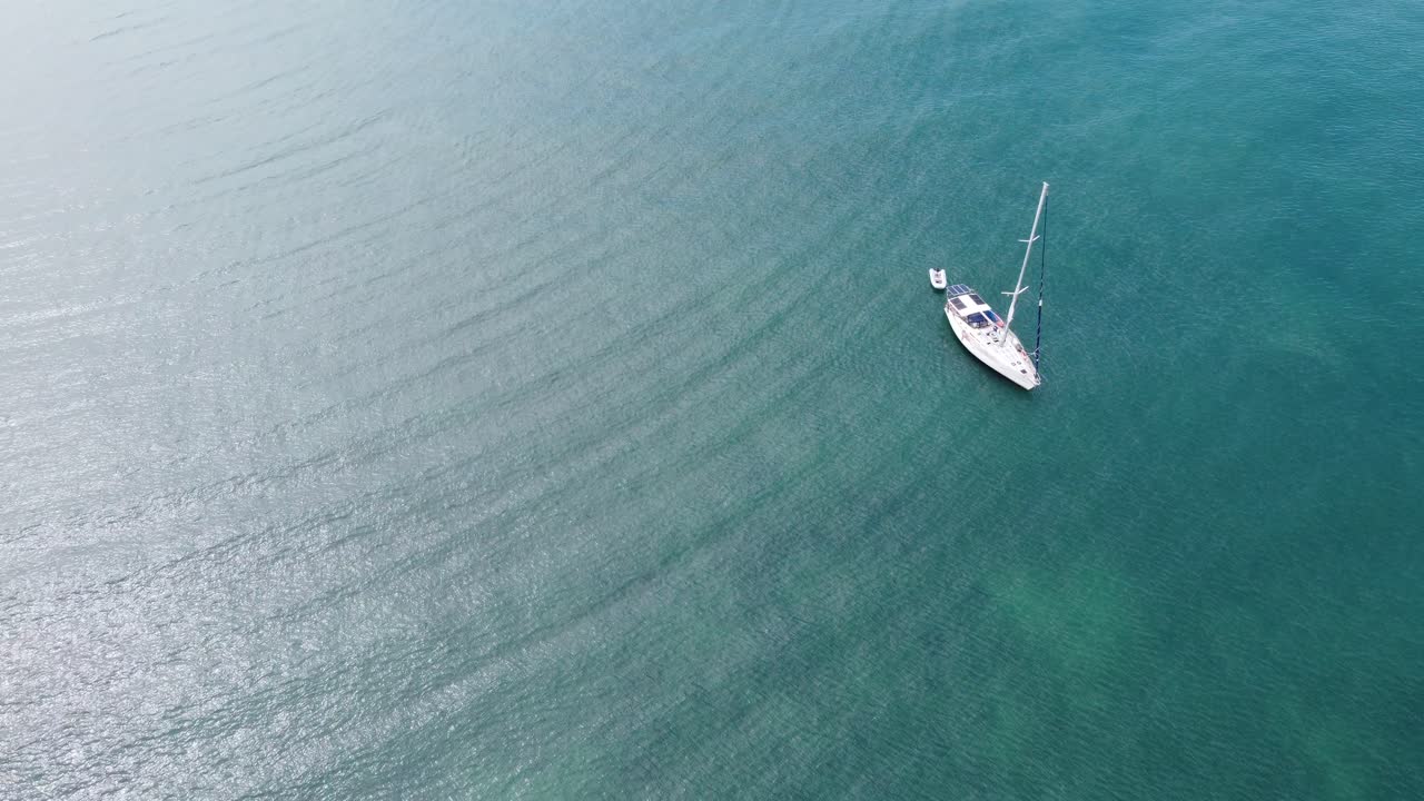 Catamaran boat sailing on turquoise blue sea water, aerial drone maritime transport