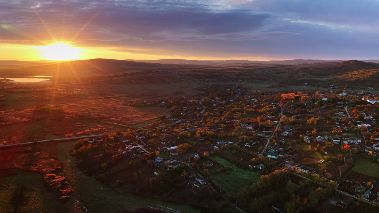 Aerial drone view of a Moldovan village surrounded by autumn trees and farmlands during sunset
