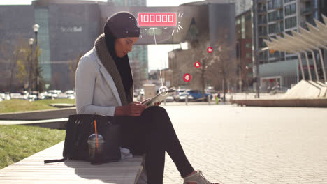 animation of mixed race woman wearing hijab in street using tablet computer with floating heart symb