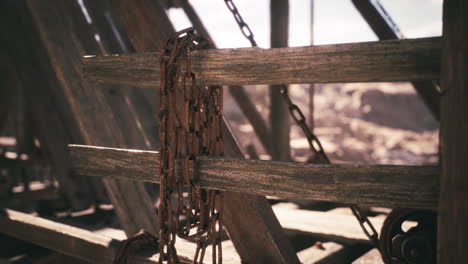 rusted chains hanging on weathered wooden beams in an abandoned structure