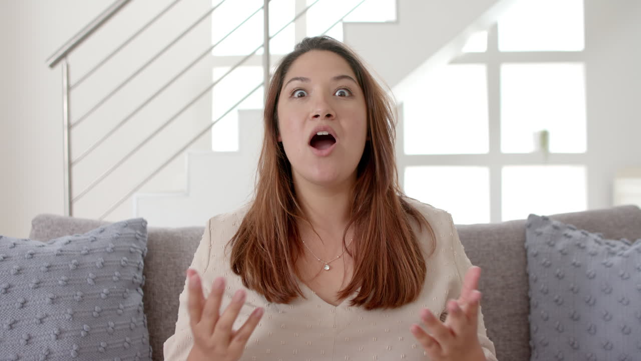 행복한 플러스 사이즈 혼인 여성이 비디오 통화를 하고 집의 이 나는 거실에서 이야기하고, 느린 동작